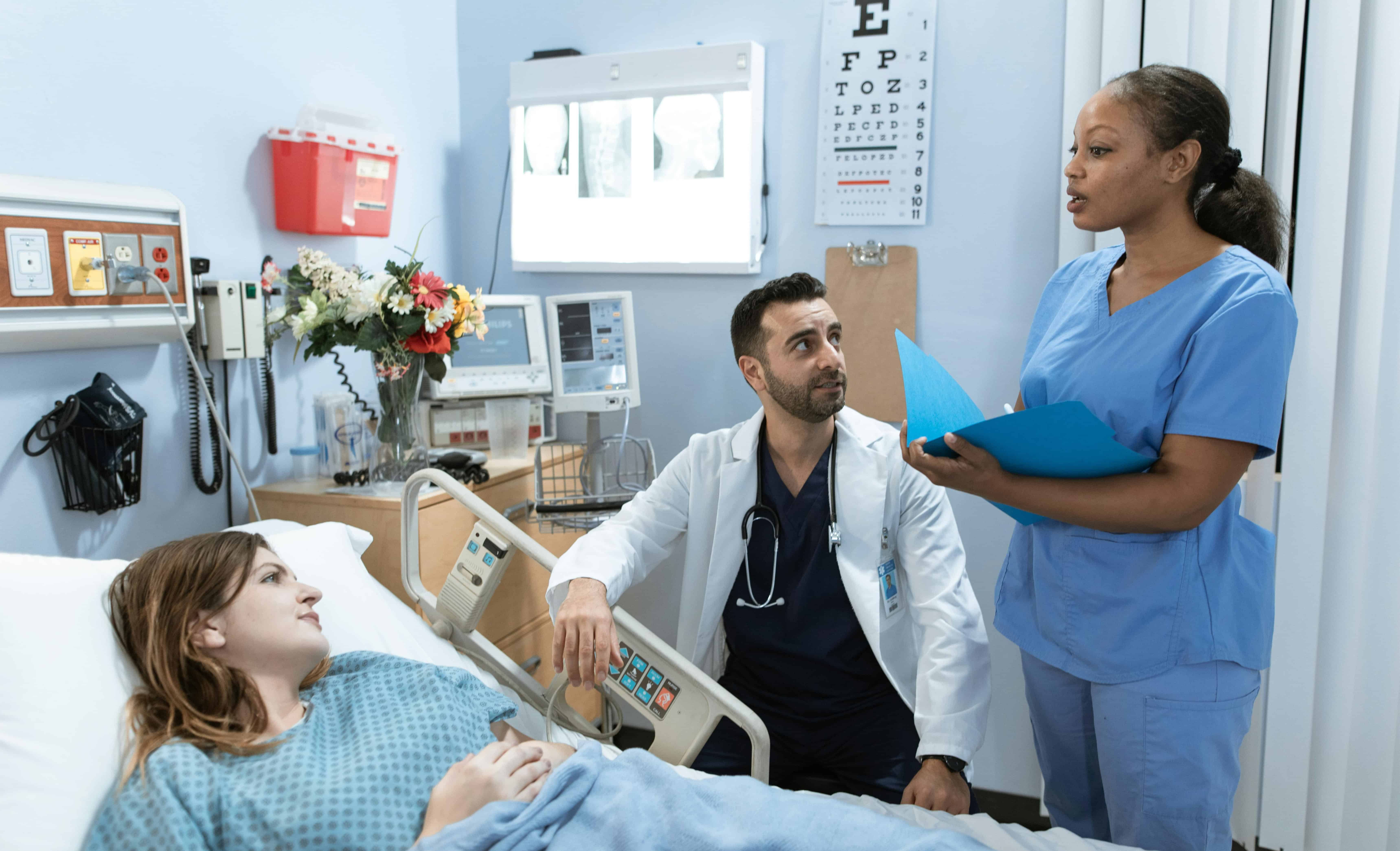 Nurse assisting patient and family member at bedside in hosptial