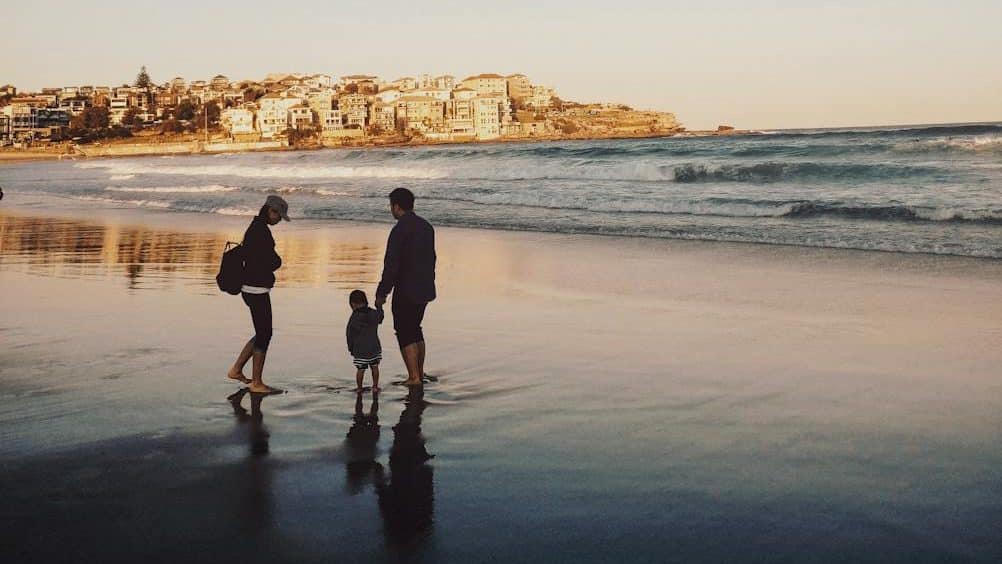 man and woman walking with boy in seashore